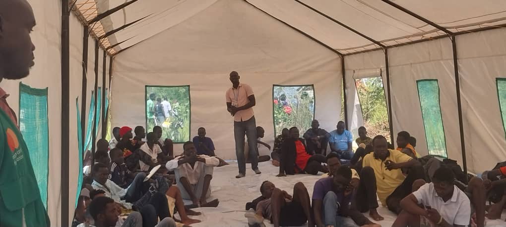 Community members attending a group session inside a tent